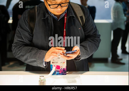 Barcelona, Spain. 27th Feb, 2017. A men look at One x10 mobile phones, manufactured by HTC during the Mobile World Congress wireless show in Barcelona. The annual Mobile World Congress hosts some of the world's largest communications companies, with many unveiling their latest phones and wearables gadgets. Credit: Charlie Perez/Alamy Live News Stock Photo