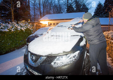 North Wales, UK.. Overnight temperature dipped below freezing with snow showers over North Wales leaving a fresh covering of snow of a few inches for villages in Flintshire. A driver clears his car this morning the village of Lixwm, Flintshire Stock Photo