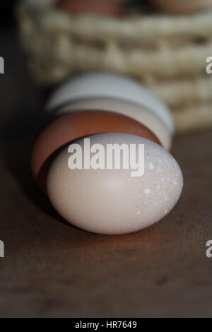 colored eggs closeup lying in a line in front of basket with eggs Stock Photo