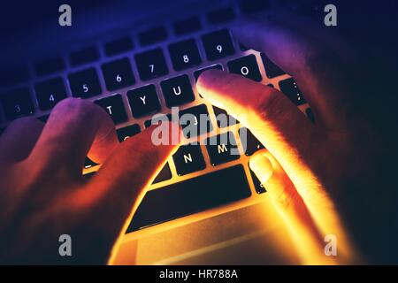 Typing on the Computer by Hacker or Programmer Concept Photo. Hands on Laptop Computer Keyboard with Strong Bright Light Coming From Back. Stock Photo