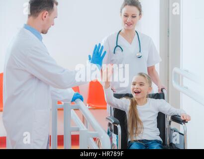 Happy Wheelchair Disabled Girl Giving High Five To Her Doctor. Mobility Impairments. Stock Photo