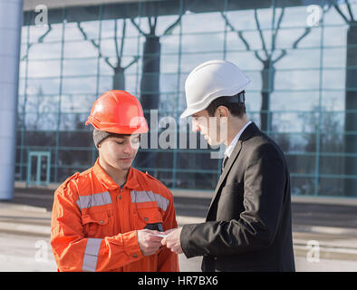 boss or Chief giving salary in an envelope to worker. Good job. Business modern background. Stock Photo