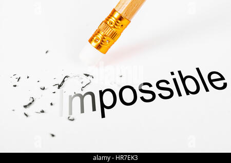 Changing the word impossible to possible with a pencil eraser on white paper. Stock Photo