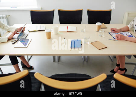 Two unrecognizable businesswoman leading negotiations sitting at opposite sides of meeting table in modern conference room Stock Photo