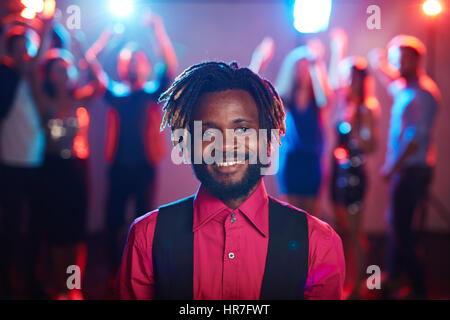 Waist-up portrait of attractive African-American with short dreadlocks smiling at camera cheerfully while hanging out in club Stock Photo