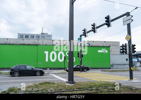 Two cars and a green storage facility with the words 100% written on it, in a crossroad in Zurich, Switzerland Stock Photo