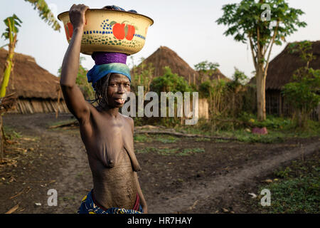 Portrait of a woman from the Holi tribe carrying a load of clothes on her head. She is carrying the load to the nearby stream to wash the clothes. In  Stock Photo