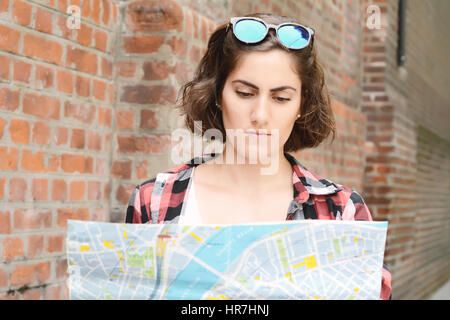 Portrait of a young beautiful tourist looking at a map. Tourism concept. Outdoors. Stock Photo
