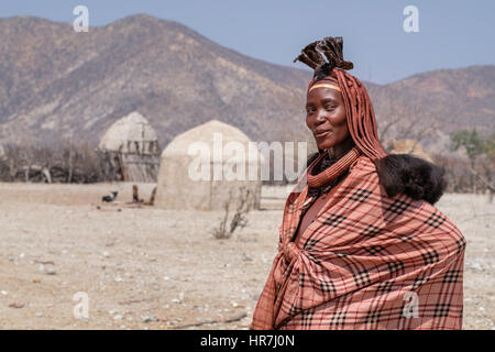 Portrait of a Himba woman in her village of mud huts. Himbas are a bantu tribe who migrated into what today is Namibia a few centuries ago. They presu Stock Photo