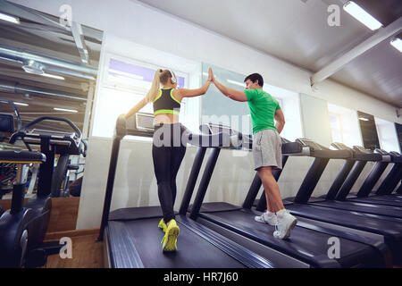 Personal trainer man with athletic girl on a treadmill in the gym. Stock Photo