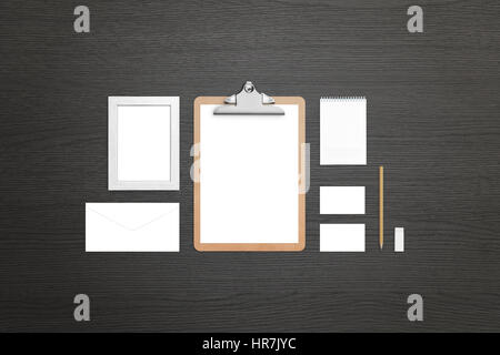 Clean stationery on black wooden table. Top view of isolated items for visual identity presentation. Clipboard, paper, pad, envelope, frame, business  Stock Photo