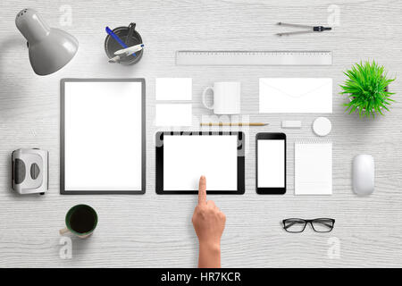 Office supplies with smart phone and tablet with isolated white screen for mockup. Corporate brand design presentation. Top view of white wooden desk. Stock Photo