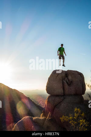 A man jumping in mid air atop a boulder appearing to be floating.Pinnacle Peak Park, Scoittsdale, Arizona, USA. Stock Photo