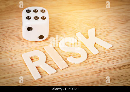 Dice and risk word wooden on wooden background, RISK conceopt. Stock Photo