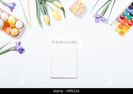 Festive Easter arrangement of flowers, painted eggs, watercolors and a notebook, top view Stock Photo