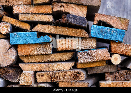 Stack of sawn boards with slices of different shapes. Two planks painted in blue color and stand out among the other Stock Photo