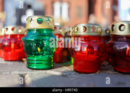 Church candlesticks with burning candles. One is green color others are red. Stock Photo