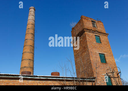 Old tower and pipe production on the background of blue sky. Stock Photo