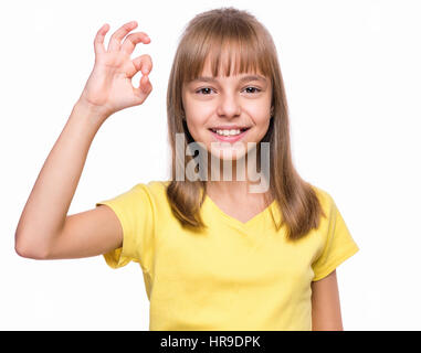 Close-up emotional portrait of attractive caucasian girl. Beautiful happy schoolgirl making ok gesture and looking at camera. Funny cute smiling child Stock Photo