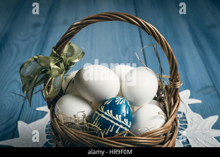Group of eggs in the basket on the blue wooden surface. Easter concept. Stock Photo