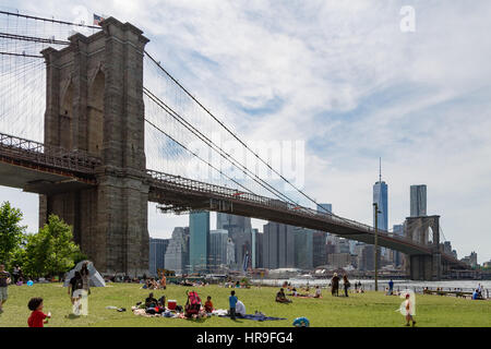 People enjoying a summer day in the park with the Brooklyn Bridge in the background Stock Photo