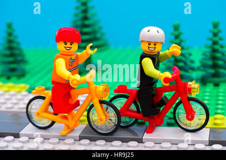 Tambov, Russian Federation - July 30, 2016 Lego boy and girl in helmets riding bicycles in park. Studio shot. Stock Photo