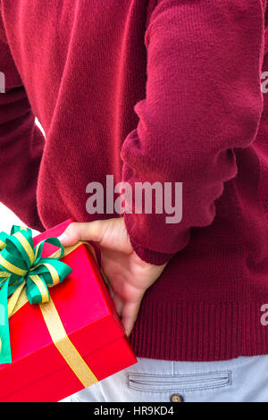 Man hiding red gift box on his back as a surprise Stock Photo