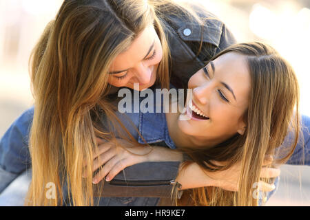Two funny affectionate friends joking and laughing together in the street Stock Photo