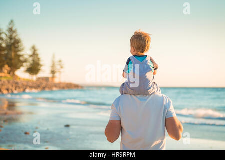 Father giving son piggyback ride on beach
