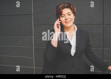young authentic business woman talks on her smart phone in the financial district for business trip Stock Photo