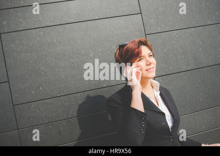 young authentic business woman talks on her smart phone in the financial district for business trip Stock Photo