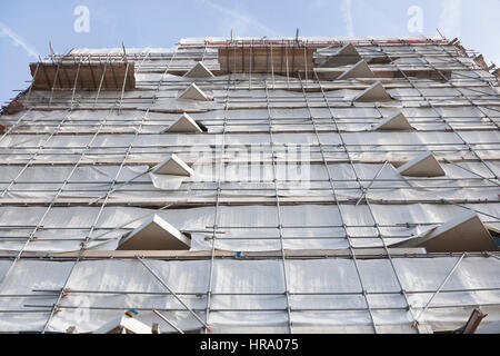 white cloth on scaffolding of high new building with concrete balconies and blue sky Stock Photo