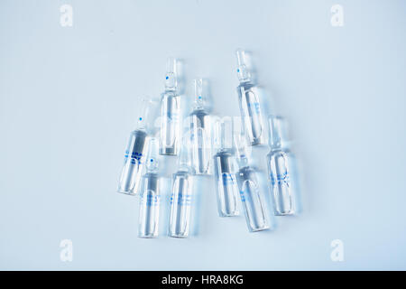 Top view of glass ampoules with medicine lying on white table Stock Photo