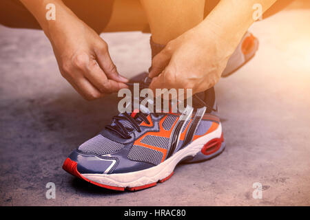 Hands tying shoes for jogging on concrete. Stock Photo