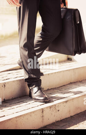 Businessman walks with his briefcase down a staircase Stock Photo