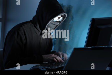 Young male thief stealing data from computer Stock Photo