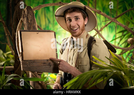 Cheerful vintage explorer in the jungle with map and blank sign Stock ...