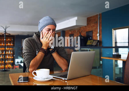 Worried shoked man looking on laptop at cafe Stock Photo