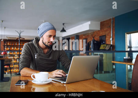 Attractive male worker is using computer in cafeteria Stock Photo