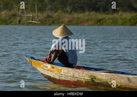 Man fishing from boat on Thu Bon River, Hoi An (UNESCO World Heritage Site), Vietnam Stock Photo