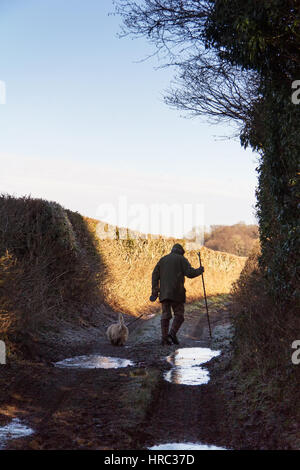 Man walking his dog along a muddy country path Stock Photo