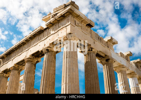 Corner detail of the ruined Acropolis, Athens showing the ancient fluted Doric columns against a cloudy blue summer sky Stock Photo