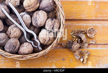 Walnuts with nutcracker in a basket on the table Stock Photo