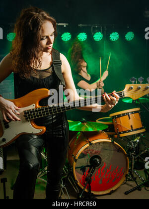 Photo of a female bass player and drummer of a rock band playing on stage. Stock Photo