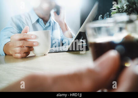 co working website designers working at office and holding a cup of coffee,working on smart phone and digital tablet computer docking on smart keyboar Stock Photo