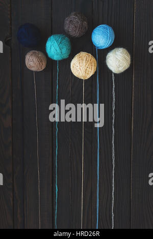 Five multicolored bolls of yarn on dark wooden surface. Top view Stock Photo