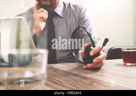 business man using VOIP headset with digital tablet computer docking smart keyboard, concept communication, it support,on wood desk Stock Photo