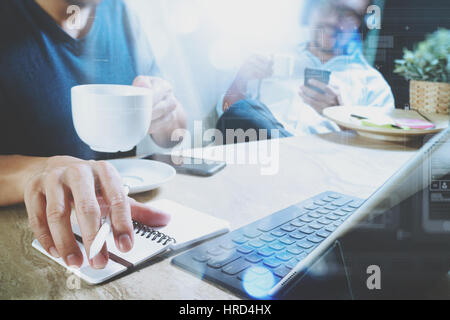 co working website designers working at office and holding a cup of coffee,working on smart phone and digital tablet computer docking on smart keyboar Stock Photo