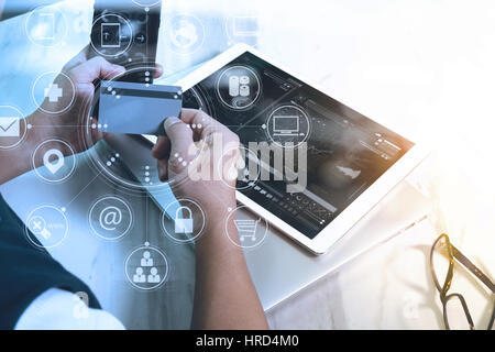 young man shopping on line with smart phone is listening music with headphones is holding a credit card on his hand at home,omni channel graphics inte Stock Photo