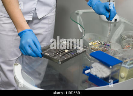 Close-up view of hands of the dentist holding dental instruments and consumable materials.  Dentist preparing for working with teeth. Different dental Stock Photo